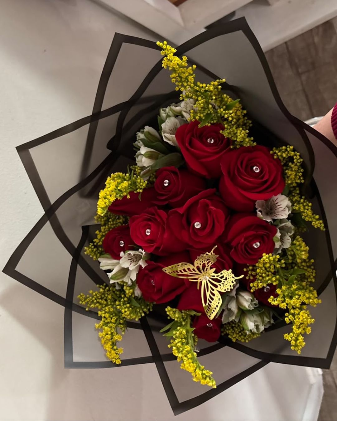 Diamond Bouquet of 12 red roses with decorative gems, white alstroemeria, yellow solidago, and a gold butterfly decoration.