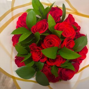 Ruscus Bouquet of 18 red roses with green foliage and white wrapping with gold trim.